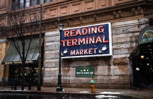 Blue and red neon sign for a market on the outside of a stone building