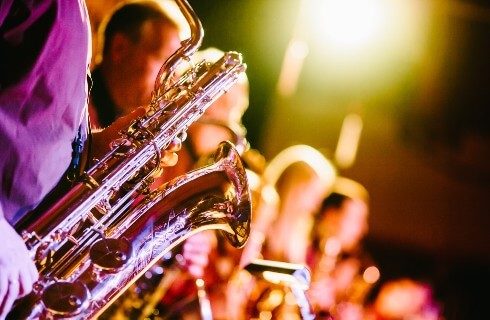 Group of people playing brass instruments with stage lights overhead