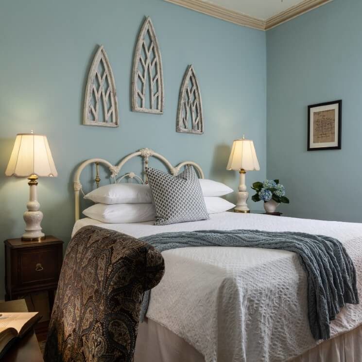 Elegant guest room with queen bed, iron headboard and side tables with white lamps