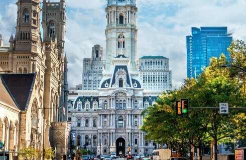 Large stone building with tall tower at the end of a city street