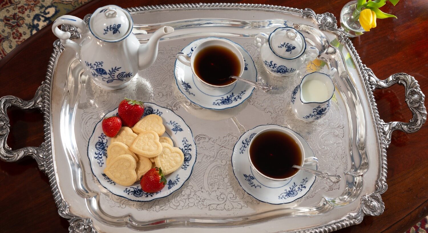 Beautiful silver platter holding white and blue dishes of a plate of cookies, two tea cups and pitcher of tea