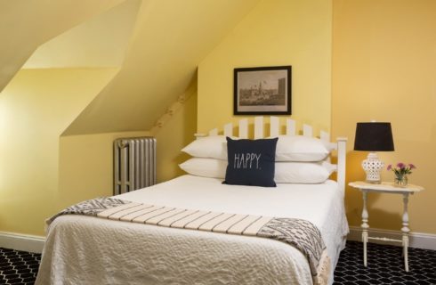 Cozy bedroom with bed, side table and lamp, and yellow angled walls