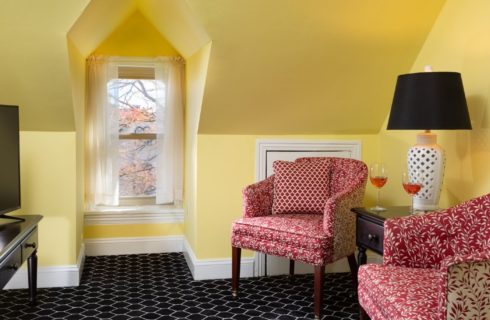 Sitting area with yellow walls, inset window, and red upholstered sitting chairs by a TV