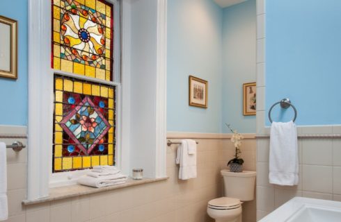 Large bathroom with tile, blue walls and beautiful stained glass windows