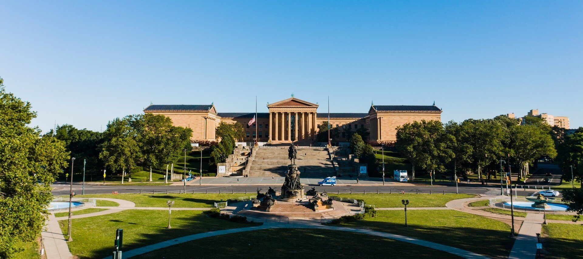 Front view of an expansive museum with columns and staircase in front of grassy area