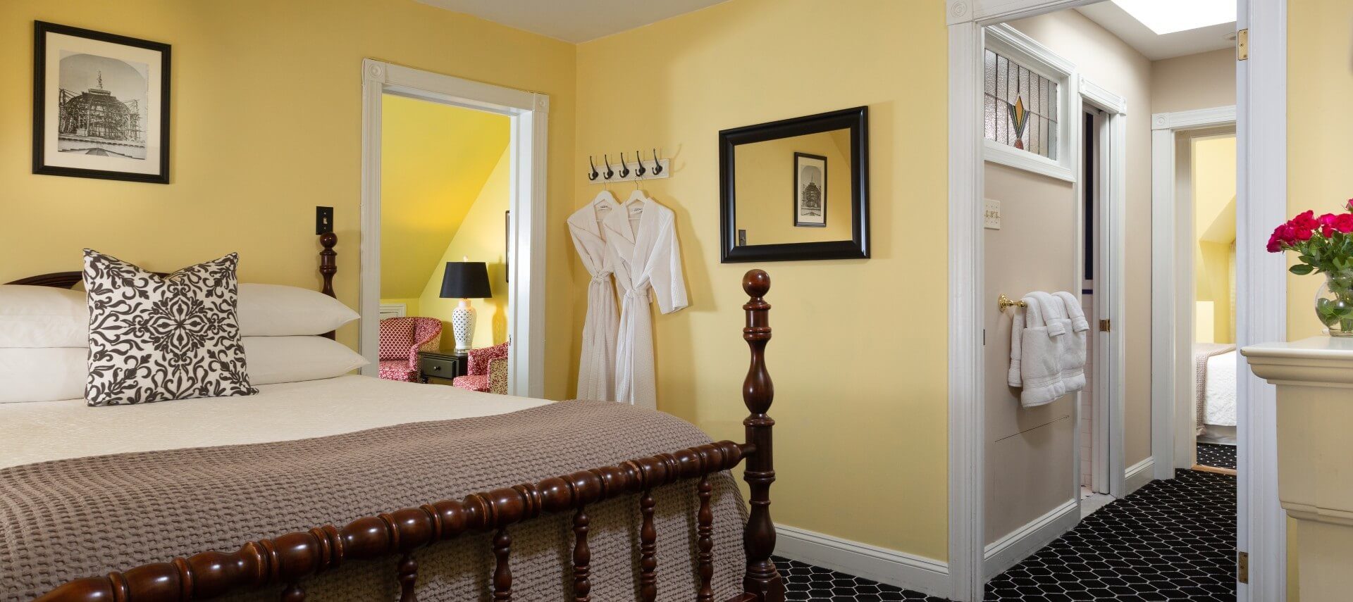 A large guest suite with queen bed, separate sitting room and hallway to an ensuite bathroom