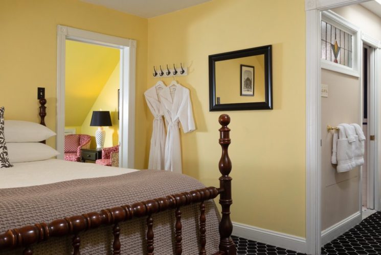 A large guest suite with queen bed, separate sitting room and hallway to an ensuite bathroom