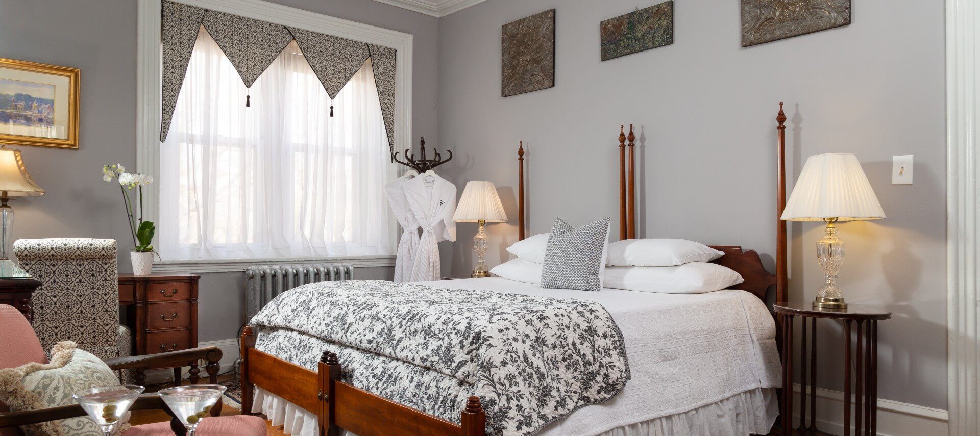 Spacious guest suite with king bed, side tables with lamps and sitting chair with a table
