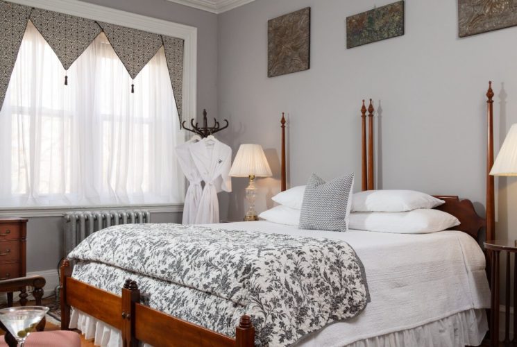 Spacious guest suite with king bed, side tables with lamps and sitting chair with a table