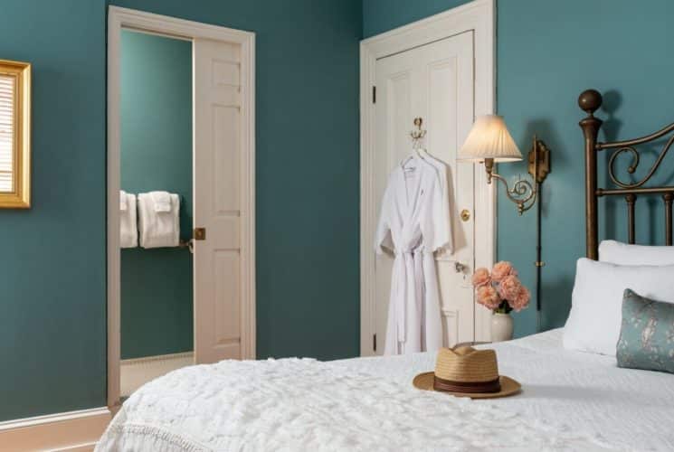 Bedroom featuring queen bed with wrought iron headboard, wall lamps and doorway into private bath