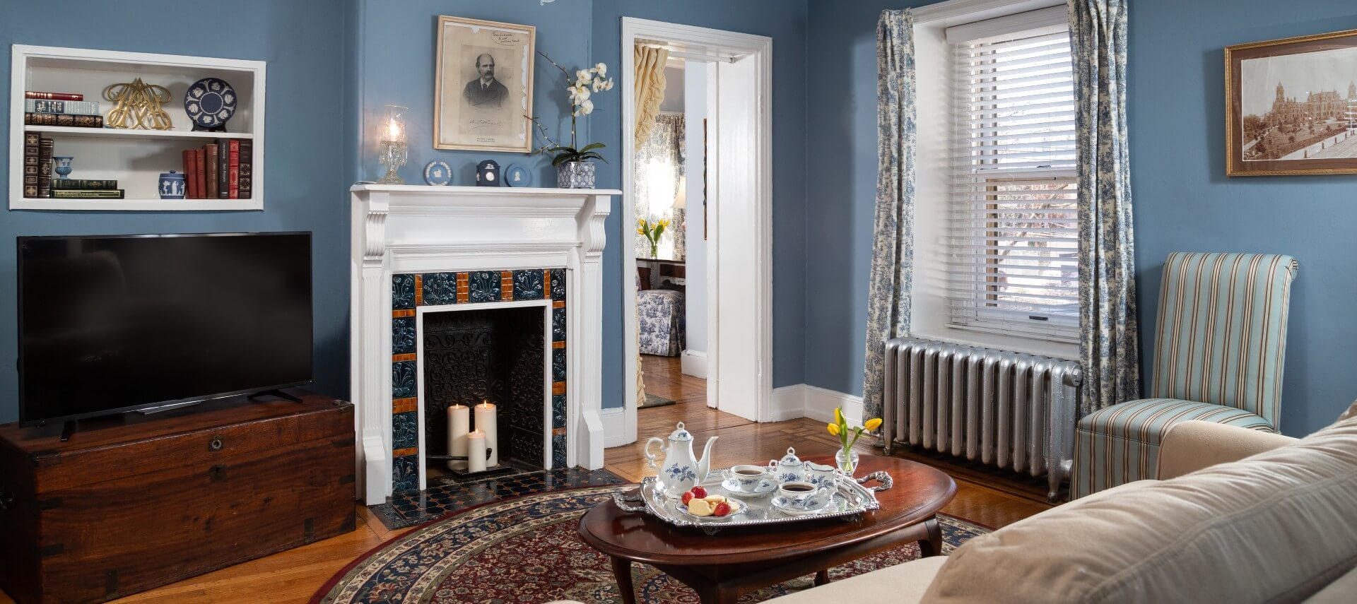 Sitting room off a bedroom with couch, table, fireplace and chest with TV