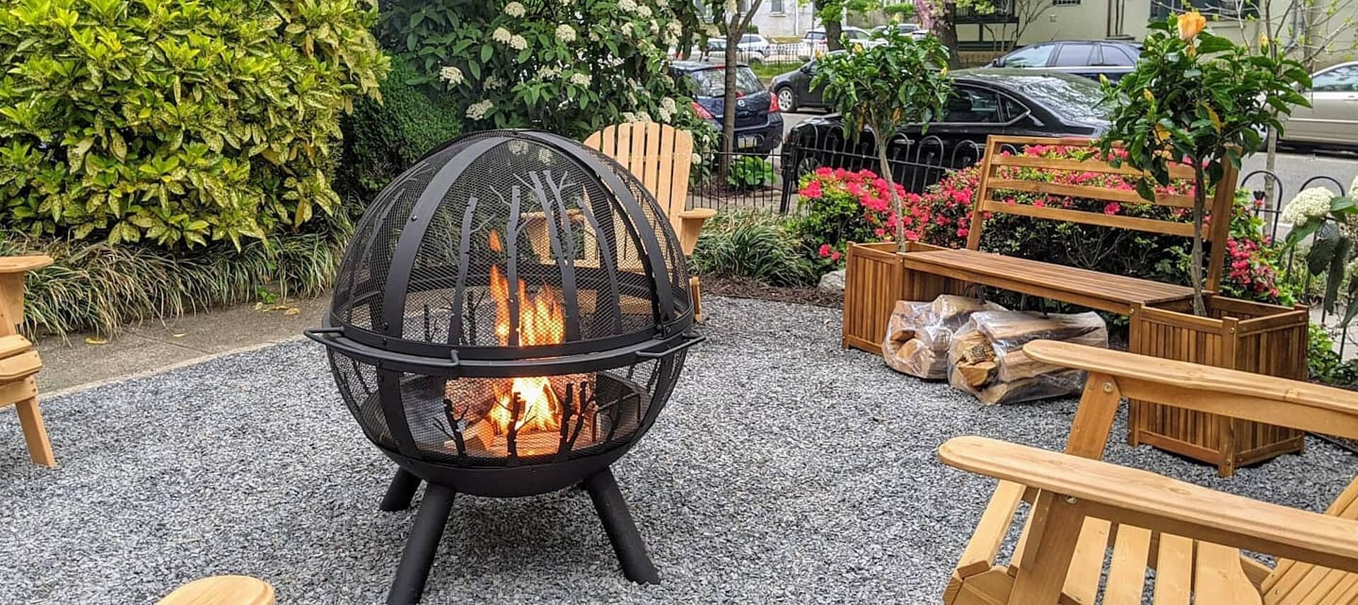 Outdoor fire pit in the shape of a globe surrounded by wooden adirondack chairs