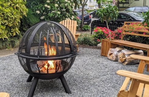 Outdoor fire pit in the shape of a globe surrounded by wooden adirondack chairs