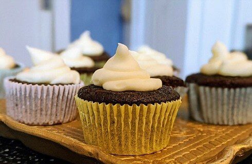 A tray holding chocolate cupcakes with white frosting